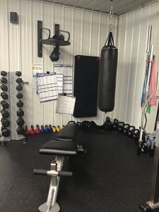 Free weights, heavy bag and bench in the strength corner at Simple and Fit